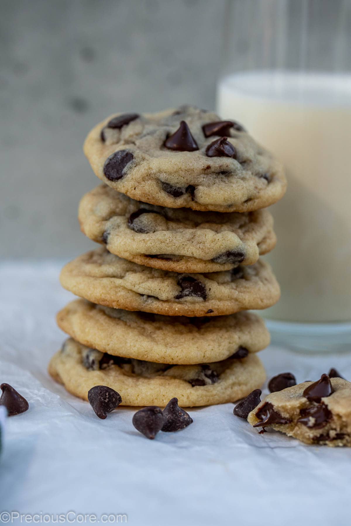 Tall stack of cookies with a glass of milk behind.