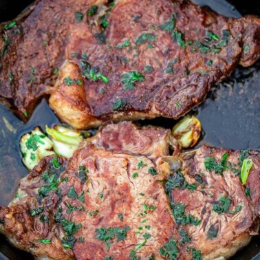 2 cooked ribeye steaks in a cast iron pan