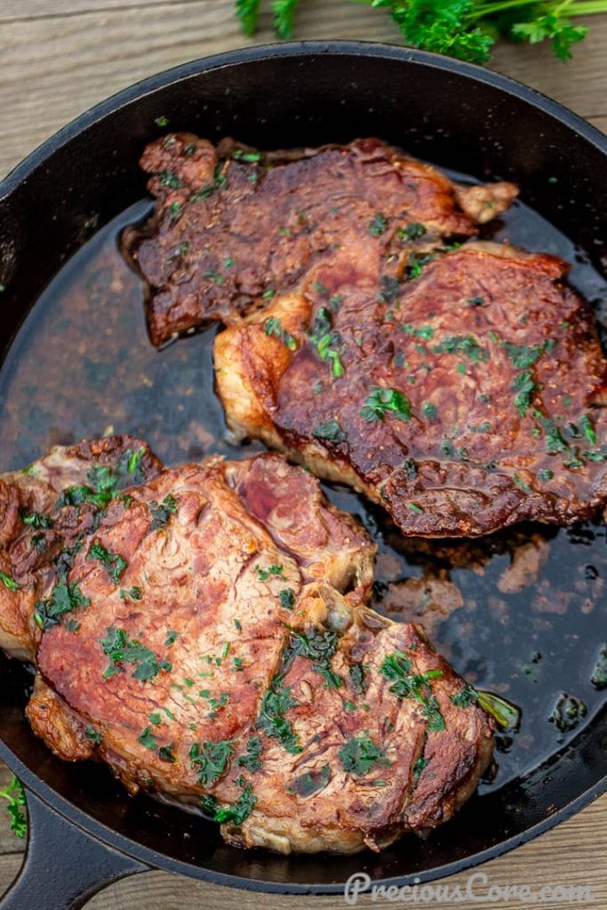 A cast iron skillet with two chunks of rib eye steak
