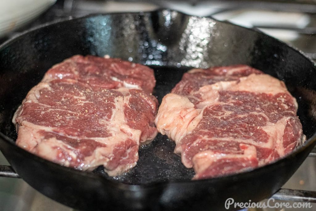 Raw ribeye steak in cast iron skillet