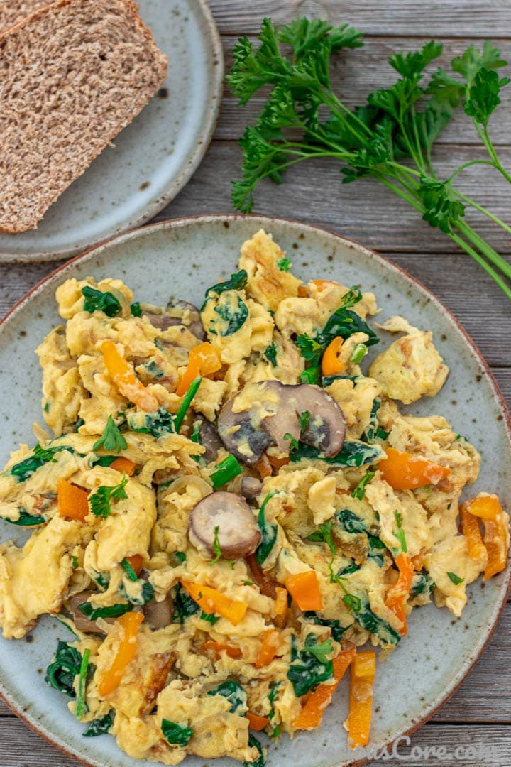 Scrambled Eggs with Vegetables on a plate with whole wheat toast on the side