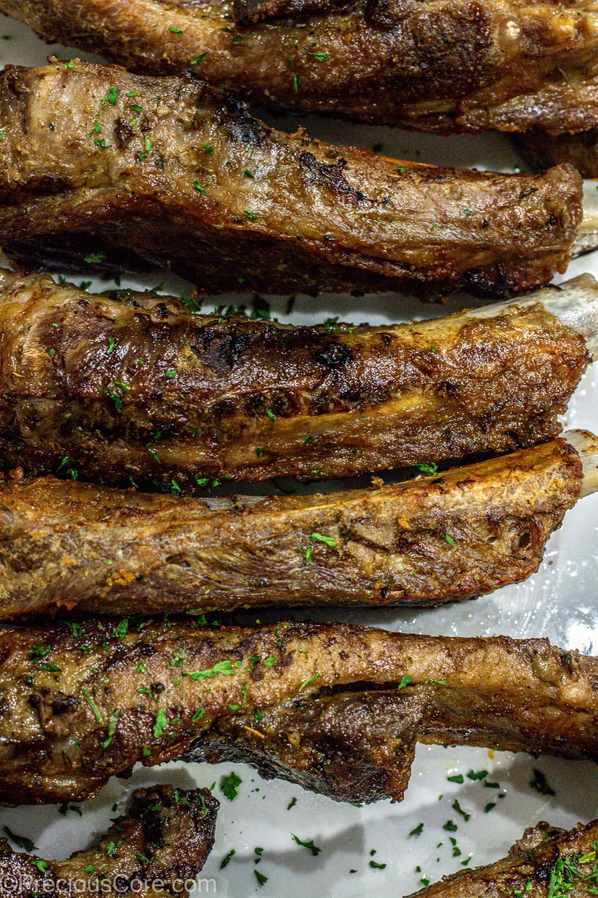 Broiled ribs on a white serving platter.