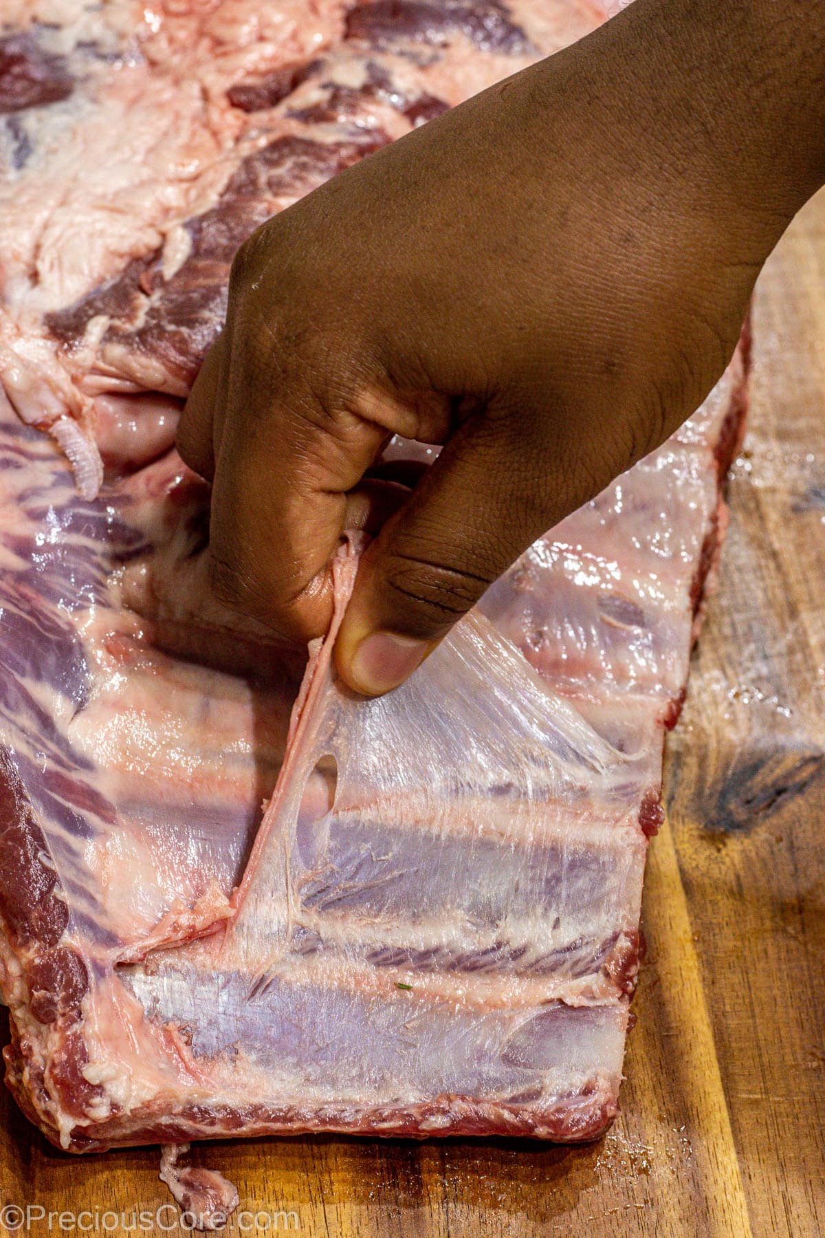 Hand removing membrane from the back of spare ribs.