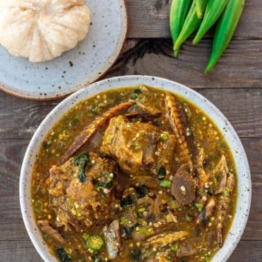 A bowl of African Okra Soup with a plate of Garri fufuf on the side