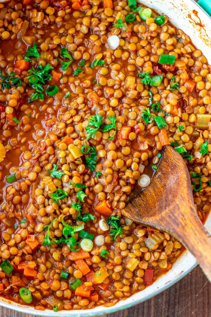 A pot of Lentil Stew garnished with chopped fresh parsley and green onions