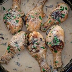 Chicken drumsticks in creamy sauce in a cast iron skillet