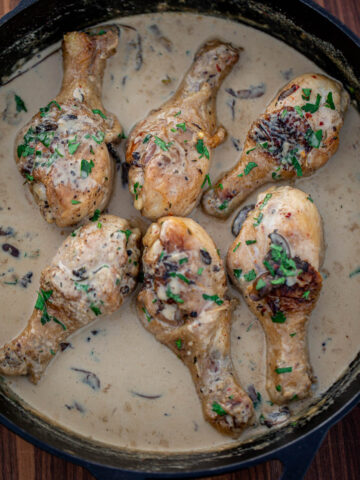 Chicken drumsticks in creamy sauce in a cast iron skillet