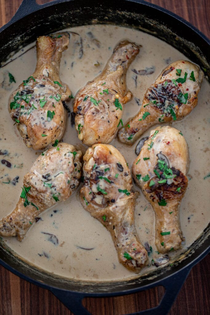 Chicken drumsticks in creamy sauce in a cast iron skillet