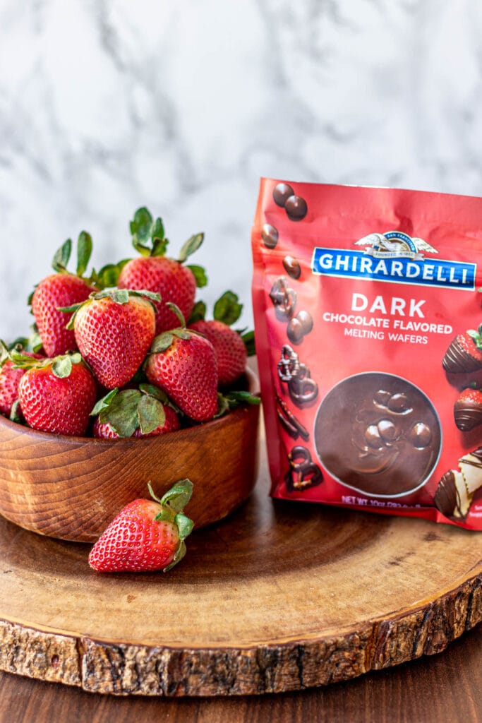 Strawberries in a bowl and melting chocolate in a bag