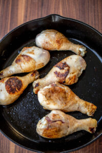 Browned chicken drumsticks in cast iron skillet