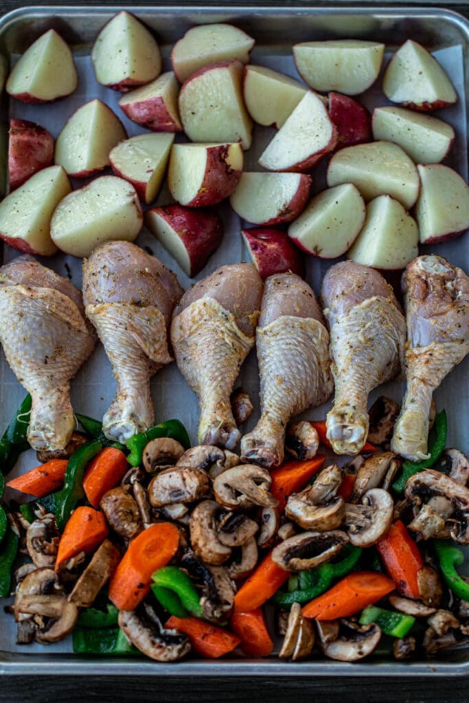 baking sheet lined with seasoned potatoes, chicken and veggies