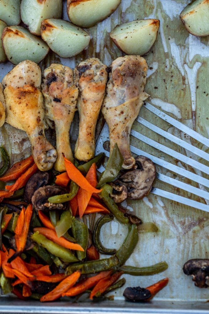 One pan chicken and potatoes and veggies being dished with a fish spatula