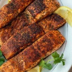 Four grilled salmon fillets on a serving platter