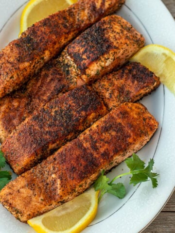 Four grilled salmon fillets on a serving platter