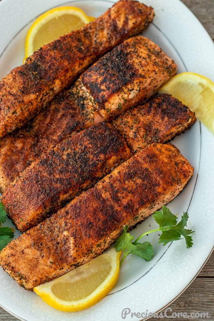 Four grilled salmon fillets on a serving platter