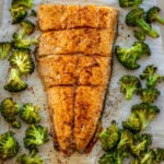 Large salmon fillet and roasted broccoli on a sheet pan