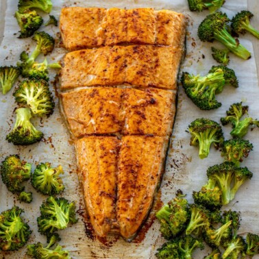 Large salmon fillet and roasted broccoli on a sheet pan