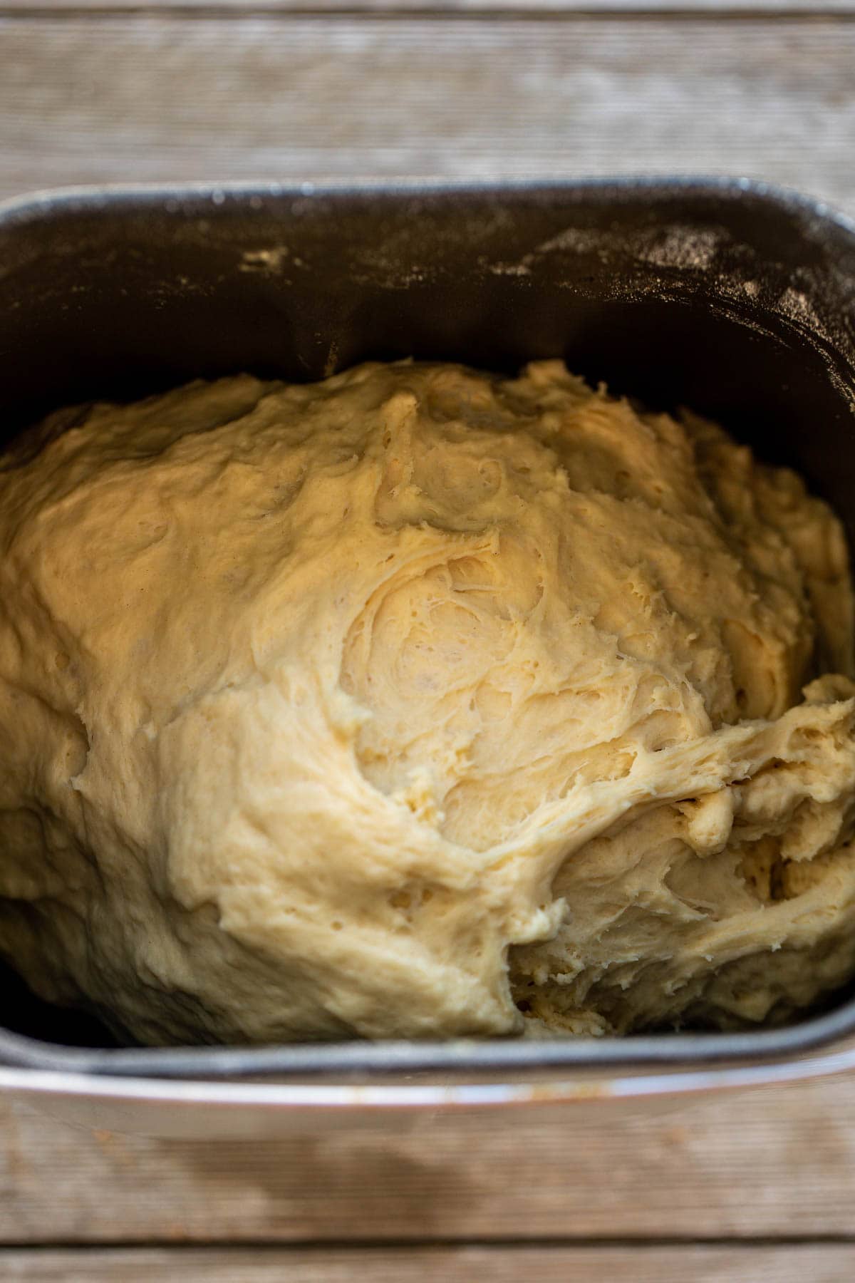 Cinnamon rolls dough in the bowl of a bread machine.