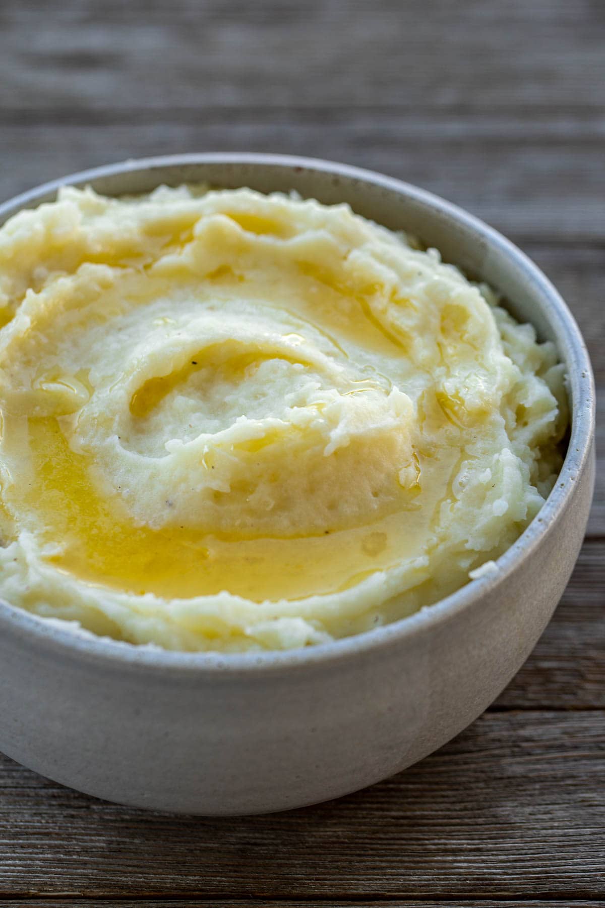 A bowl of creamy mashed potatoes topped with melted butter