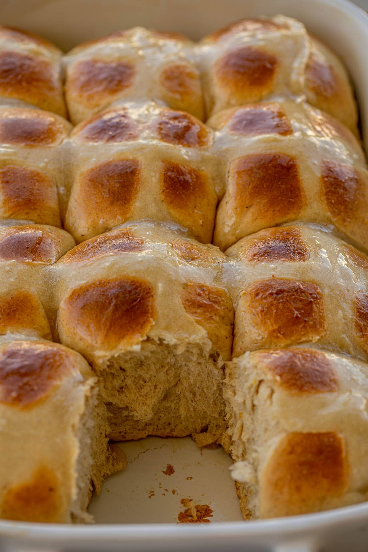 Hot Cross Buns in a baking dish with one removed
