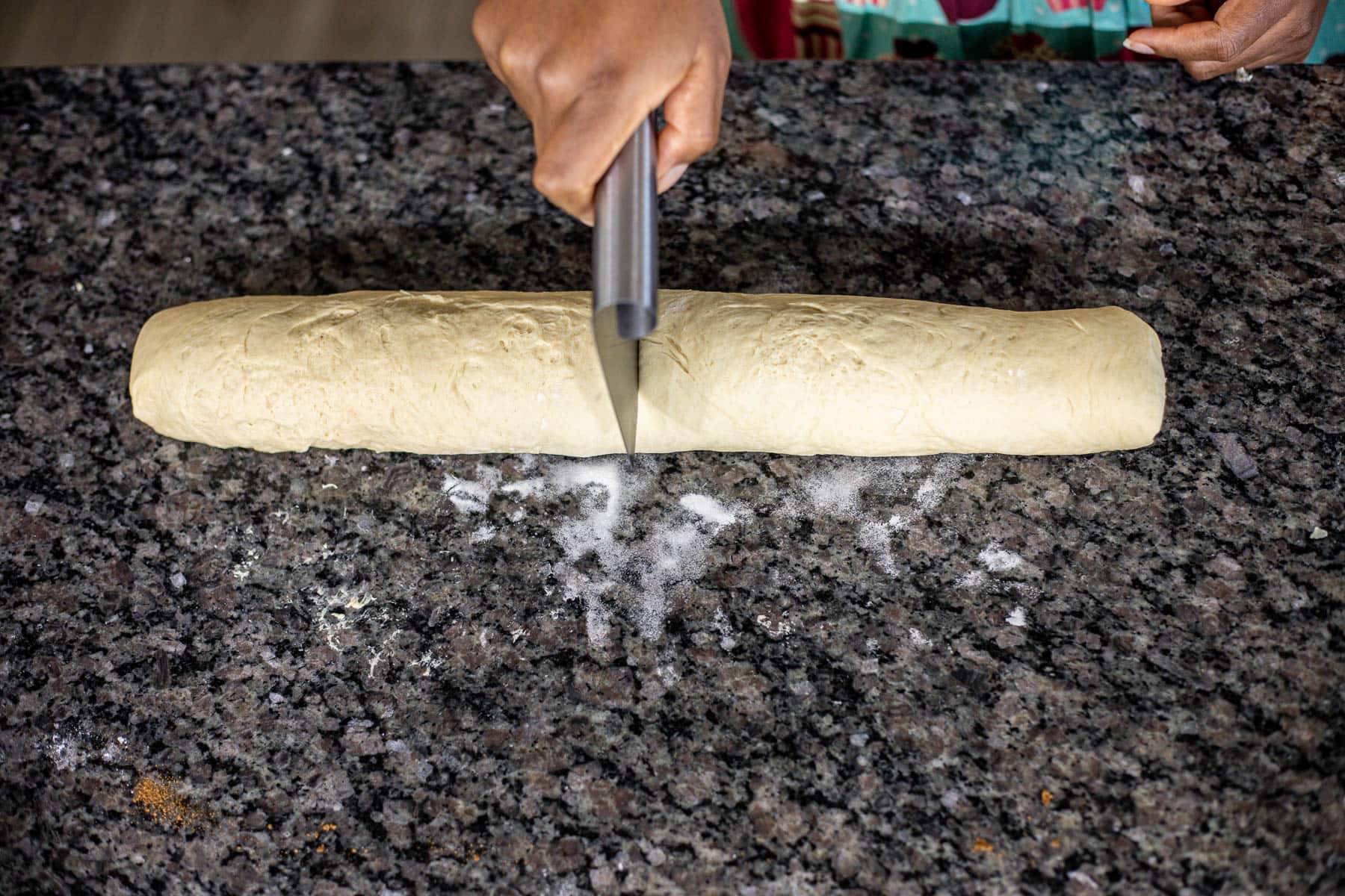 Cutting dough in the middle using a dough scraper.