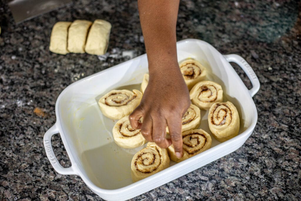 placing sweet rolls into a greased baking dish