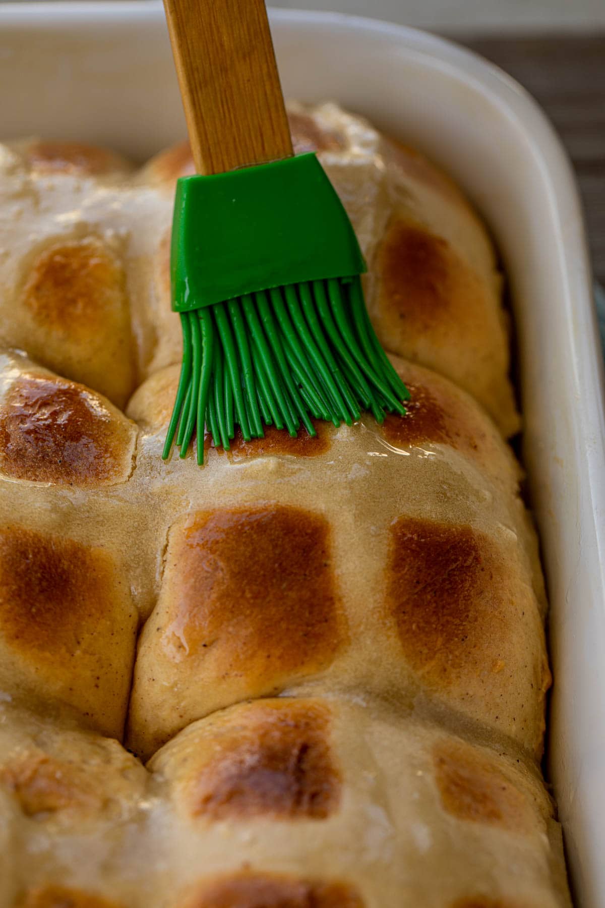 Pastry brush brushing glaze on hot cross buns