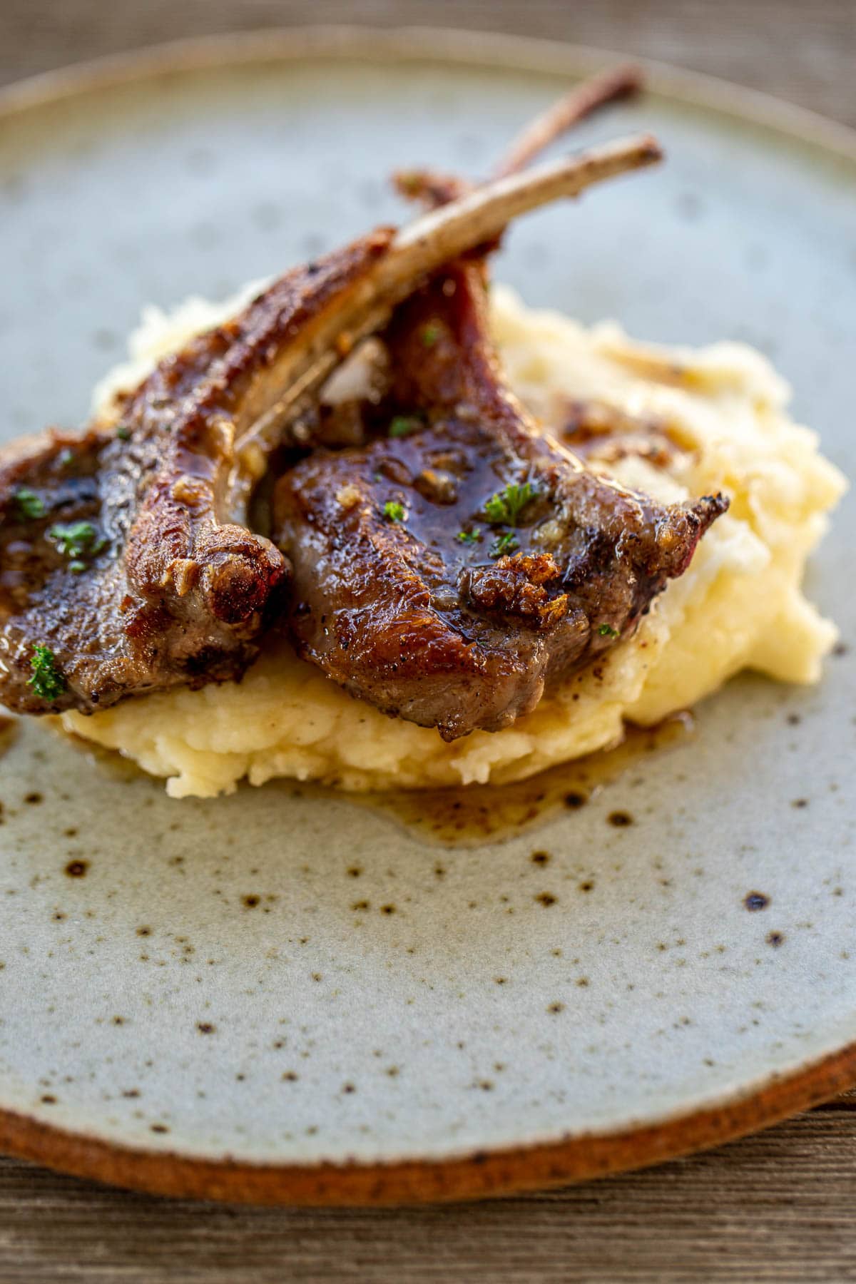 A plate with mashed potatoes and lamb chops.