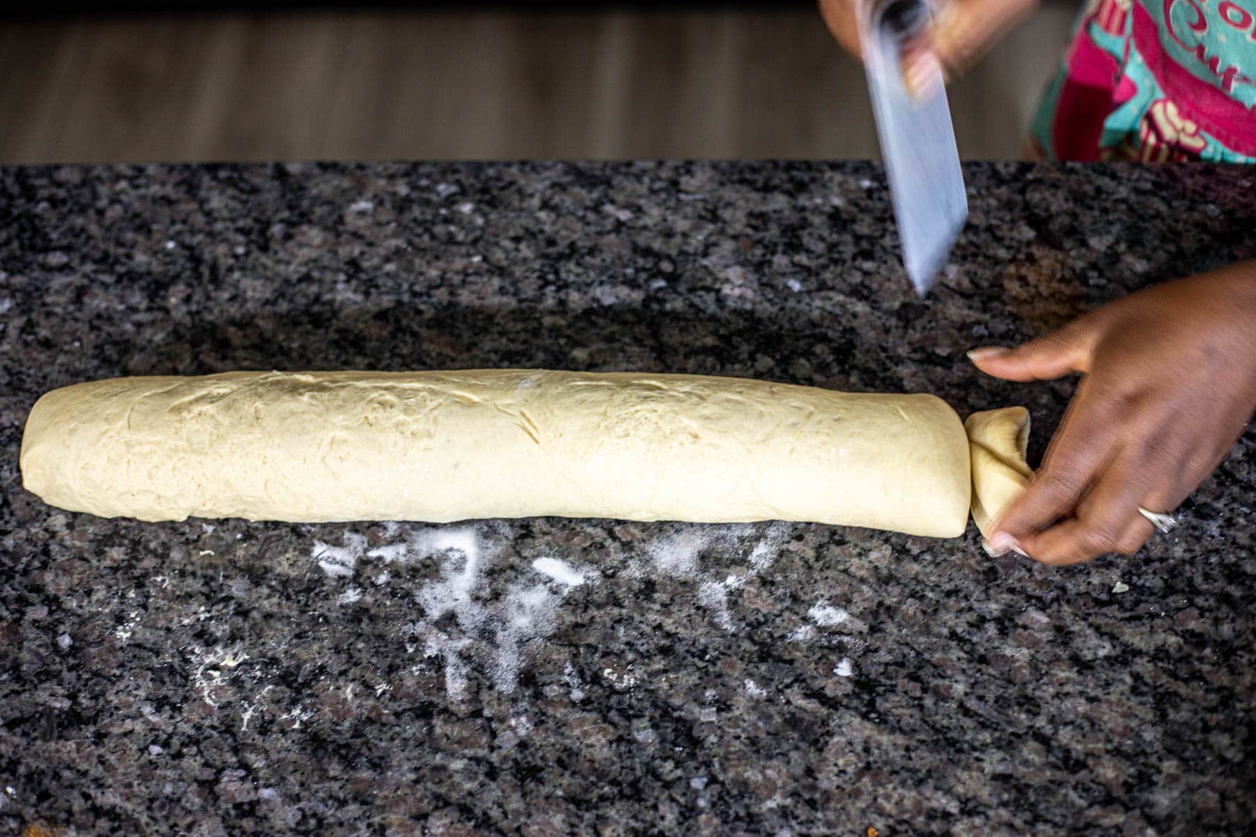 Hand trimming ends of cinnamon rolls log.