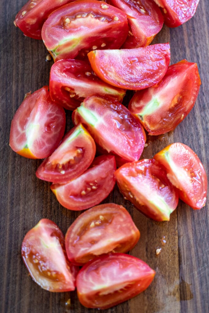 Quartered tomatoes on a chopping board.