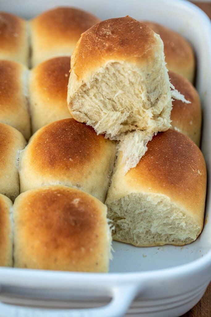 Banana bread rolls in pan with one bread roll on top showing fluffiness