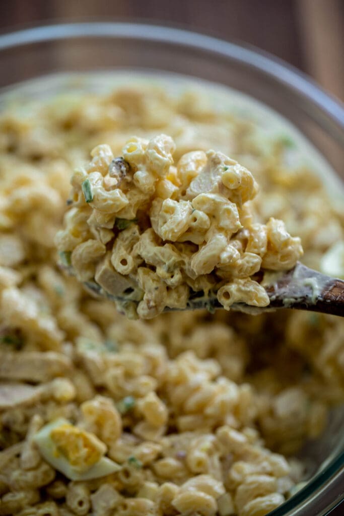 Wooden spoon lifted up of macaroni salad