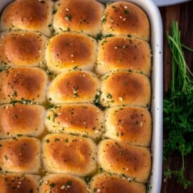 A full baking dish of dinner rolls brushed with garlic butter