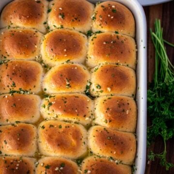 A full baking dish of dinner rolls brushed with garlic butter