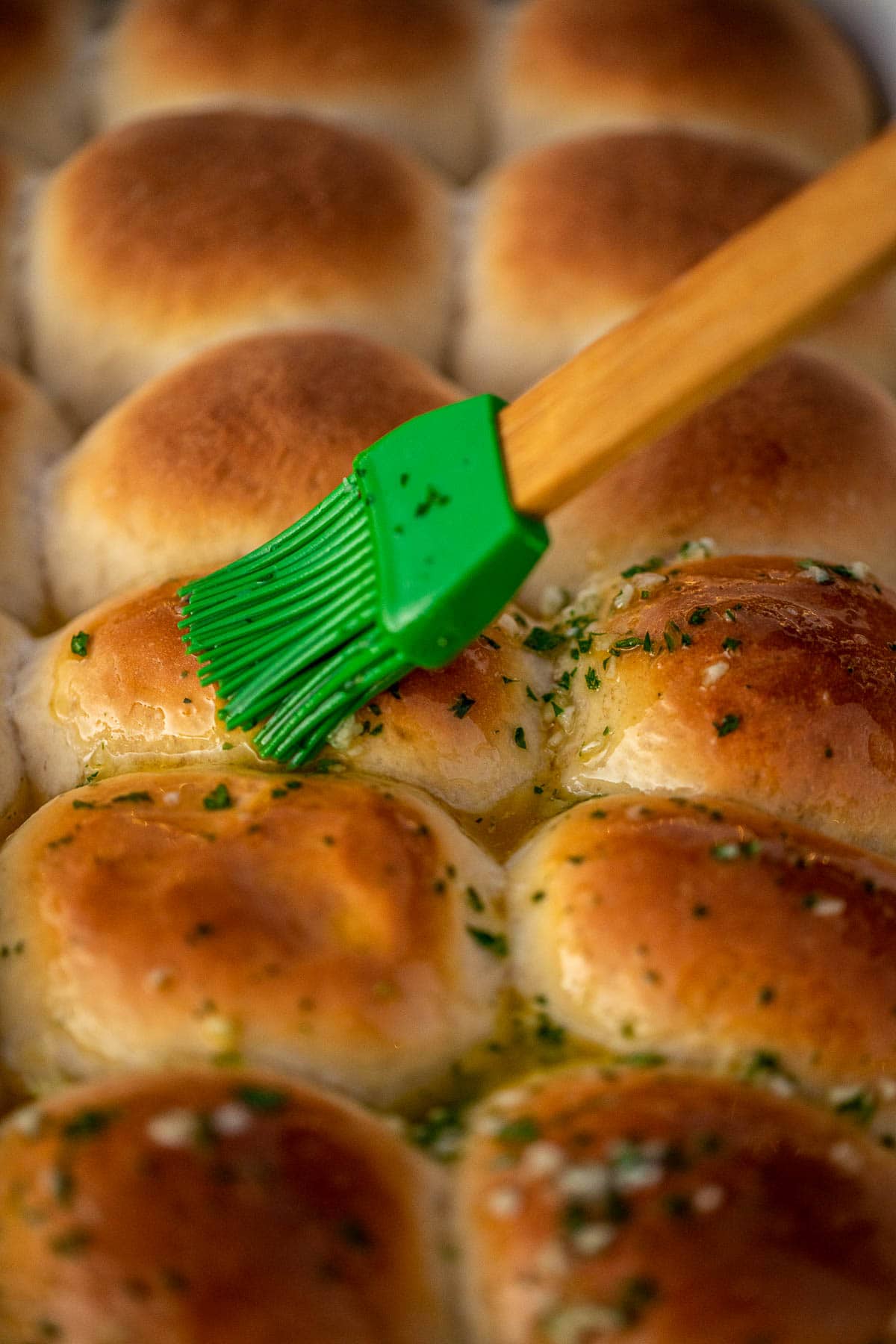 Brushing garlic butter over dinner rolls.