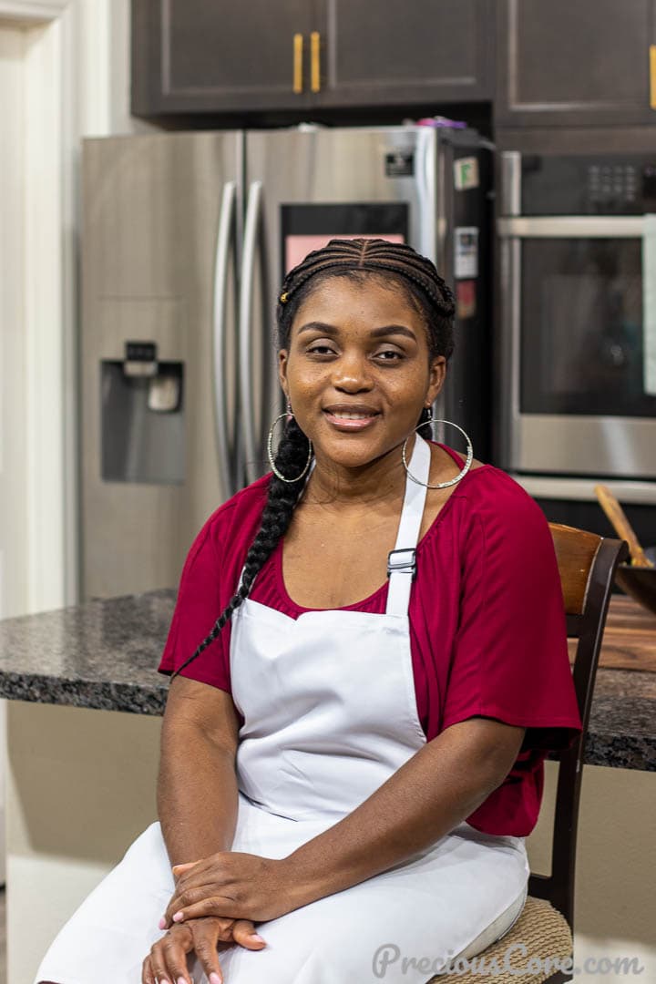 Precious Nkeih of the blog Precious Core sitting on a kitchen island. 