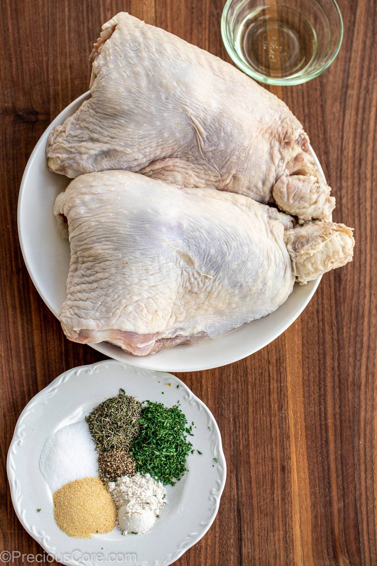 Turkey thighs, spices, herbs, and seasoning on a chopping board.