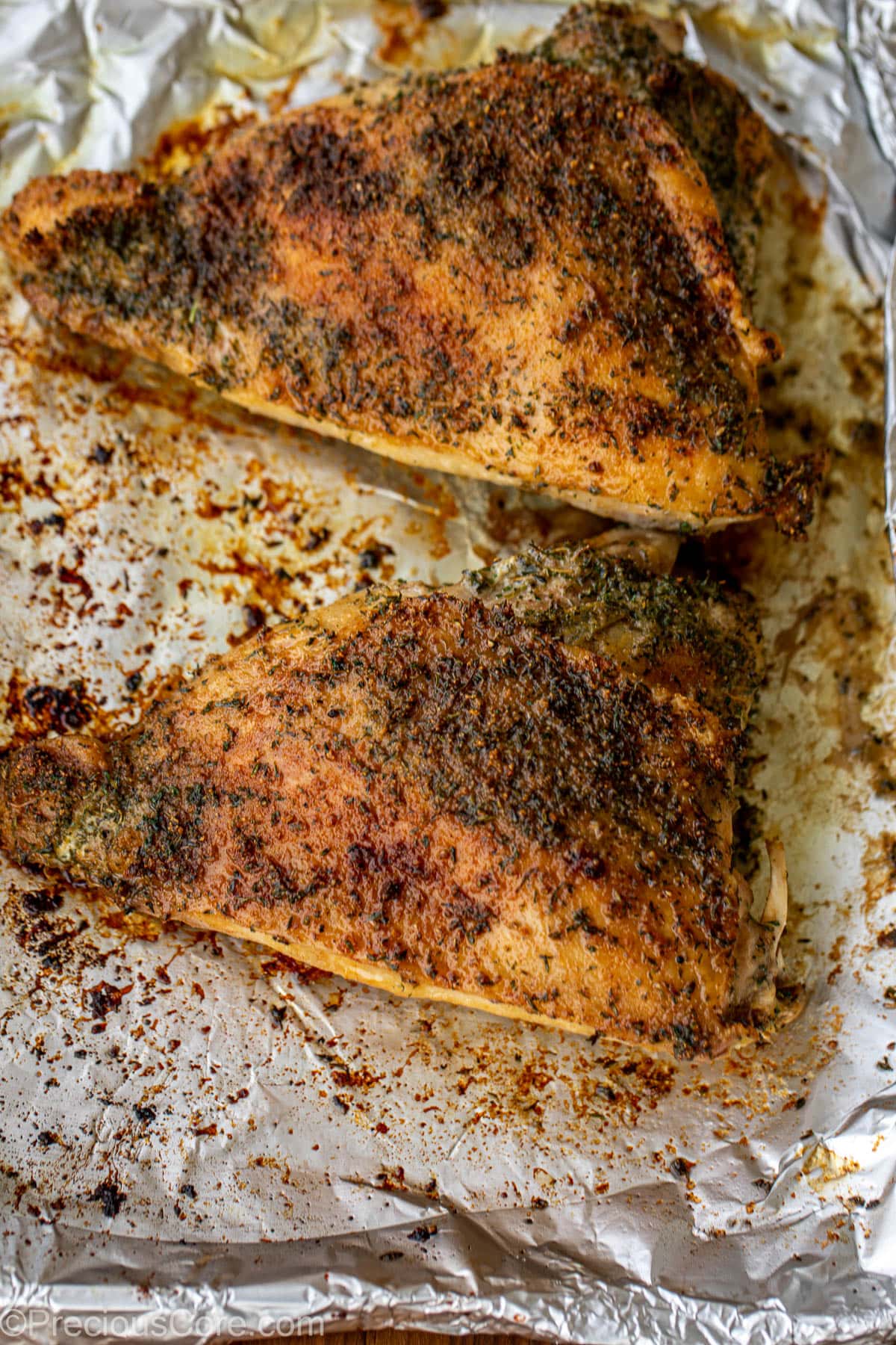 Roasted turkey thighs on a tray lined with aluminum foil.