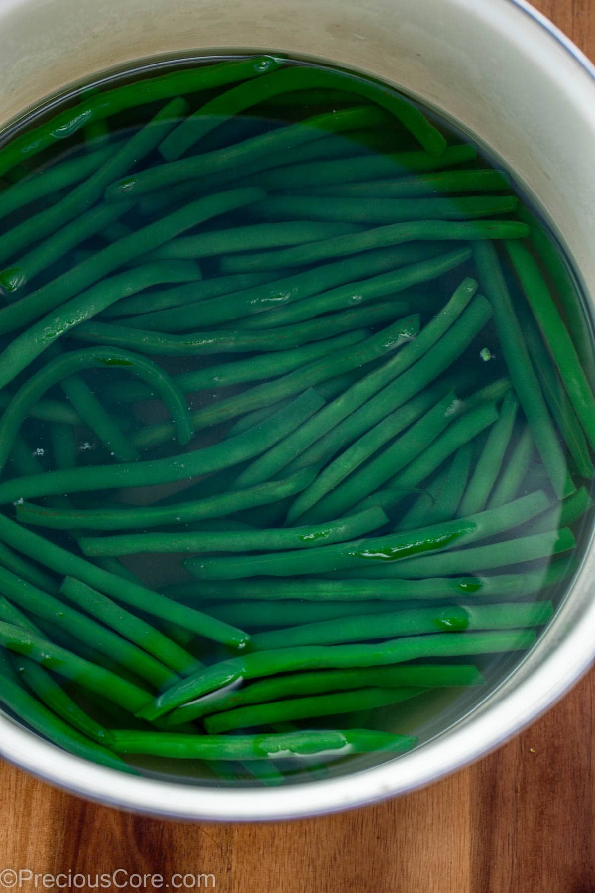Green breans in a pot of hot water.