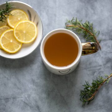 Honey lemon tea in a mug, slices of lemon nearby.