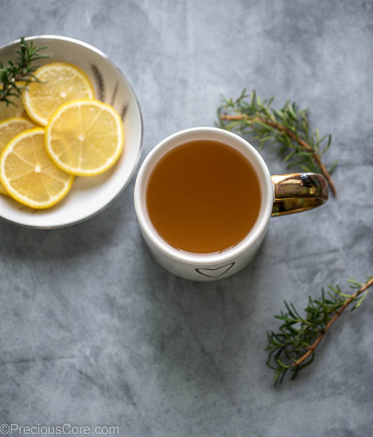 Honey lemon tea in a mug, slices of lemon nearby.