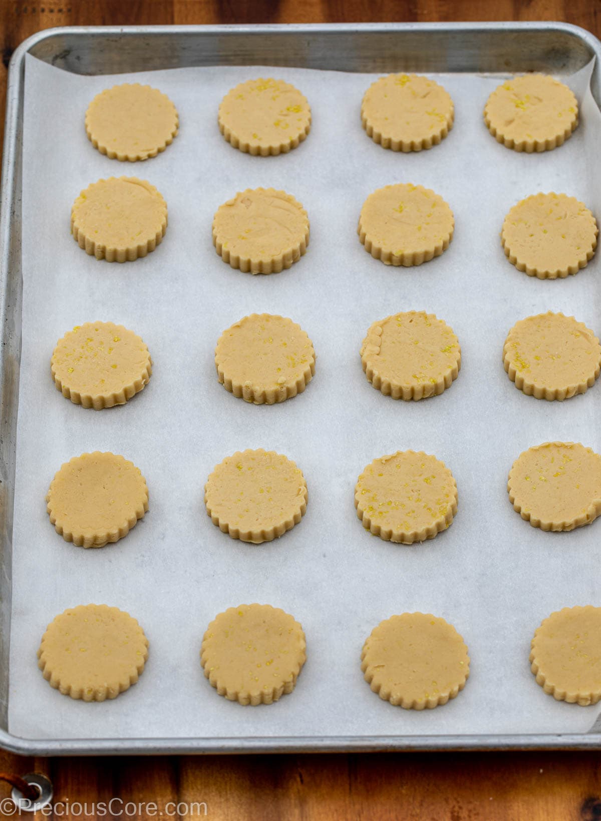 Cut-out cookie dough on baking sheet lined with parchment paper.