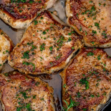 Pan seared boneless pork chops in a cast iron pan with butter underneath.