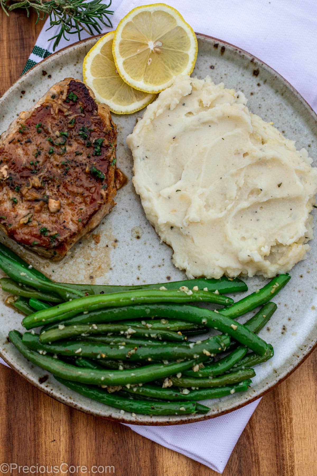Cooked pork chops in a pan with green beans and mashed potatoes.