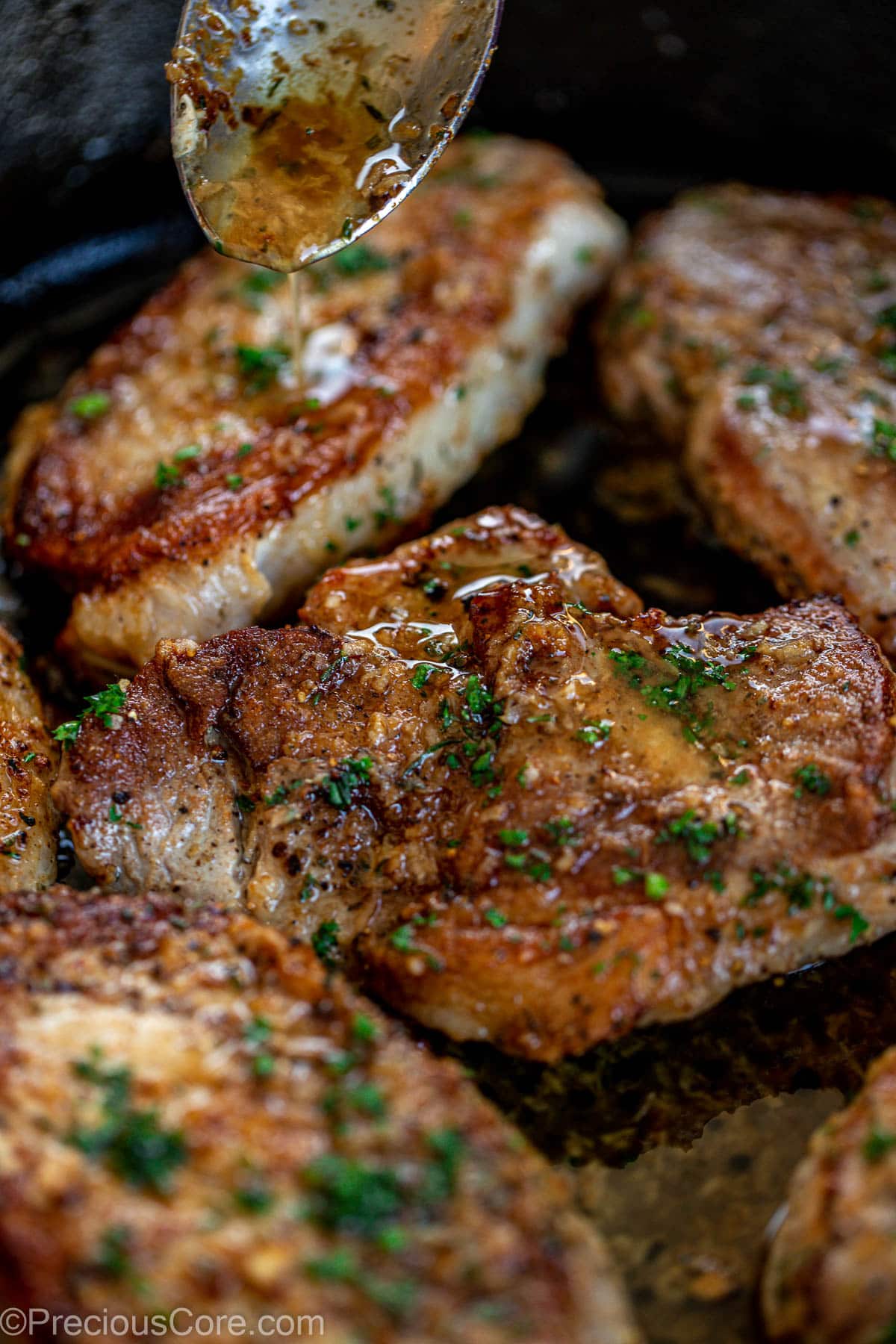 Garlic butter sauce spooning over pork chops