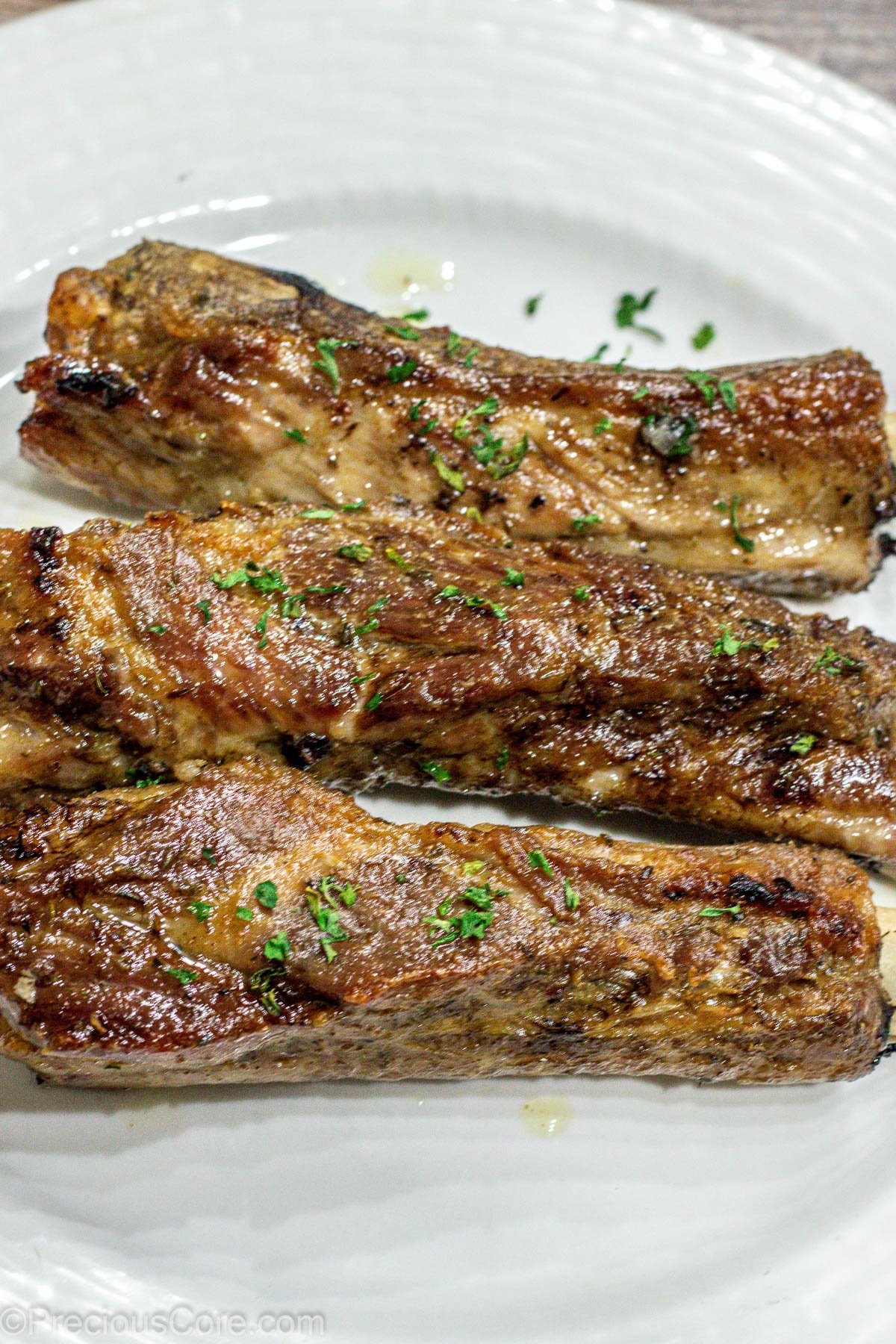 3 baked ribs on a white plate.