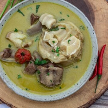 Bowl of pepper soup sitting on a round platter.