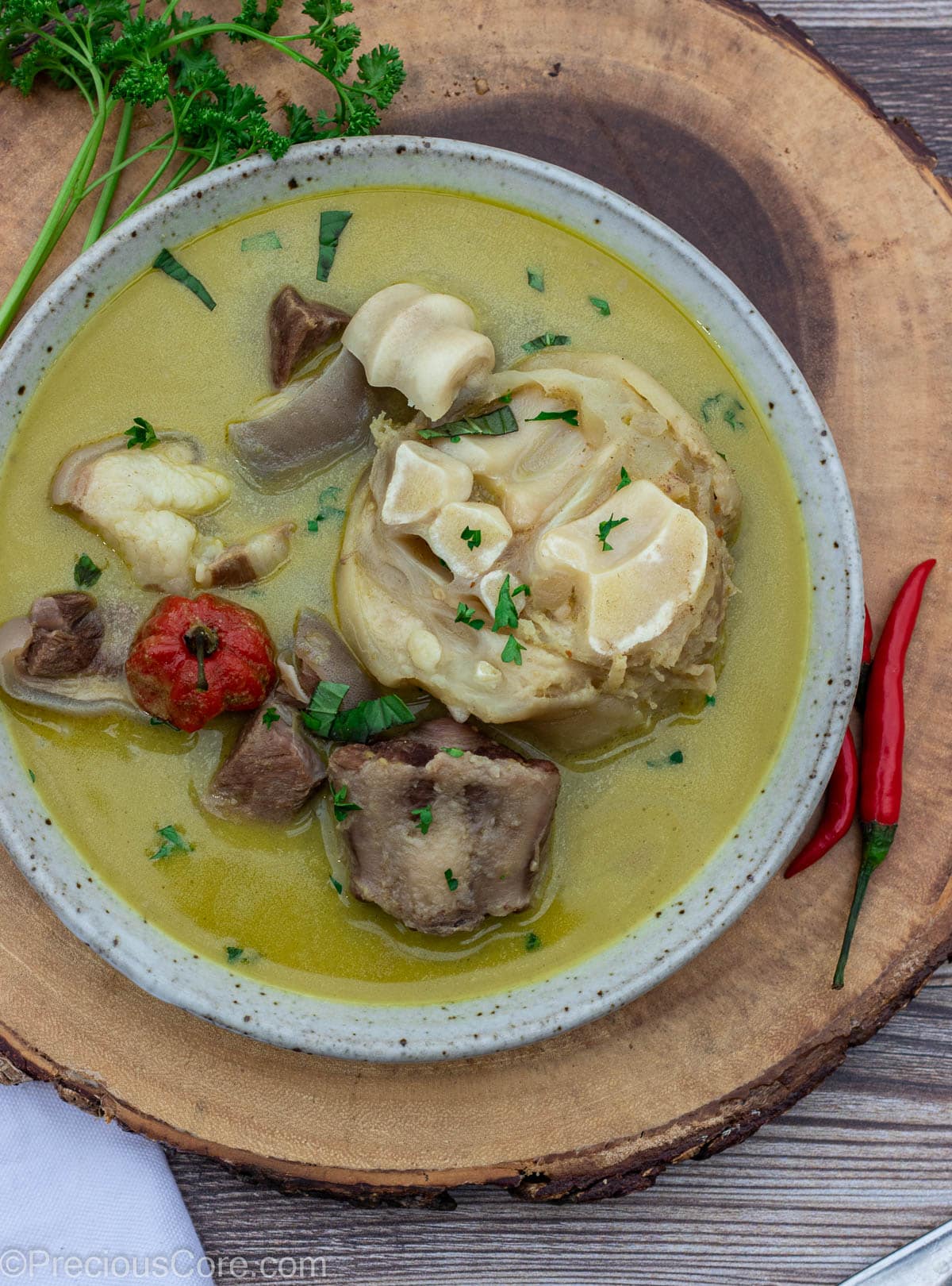 Bowl of pepper soup sitting on a round platter.