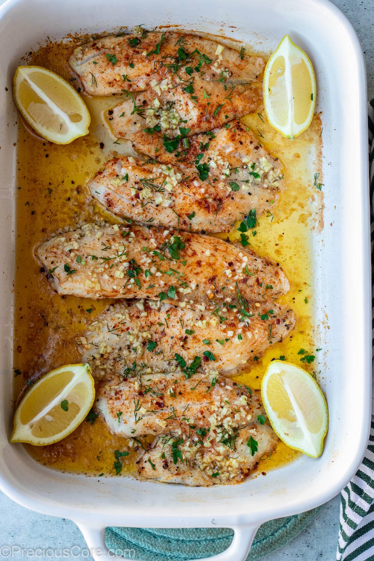 Baked tilapia fillets in baking dish.