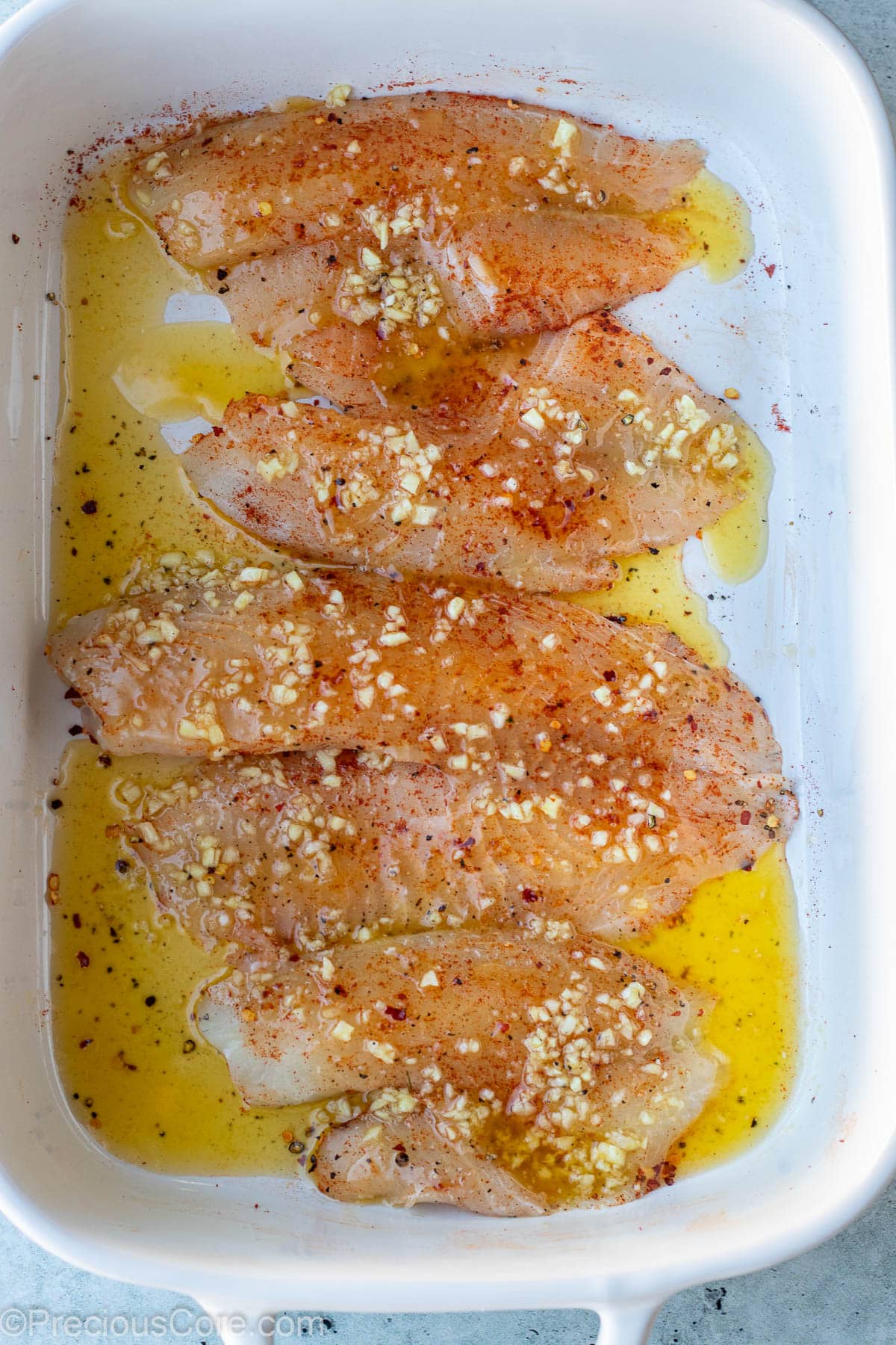 Raw fish fillets covered with garlic butter sauce.